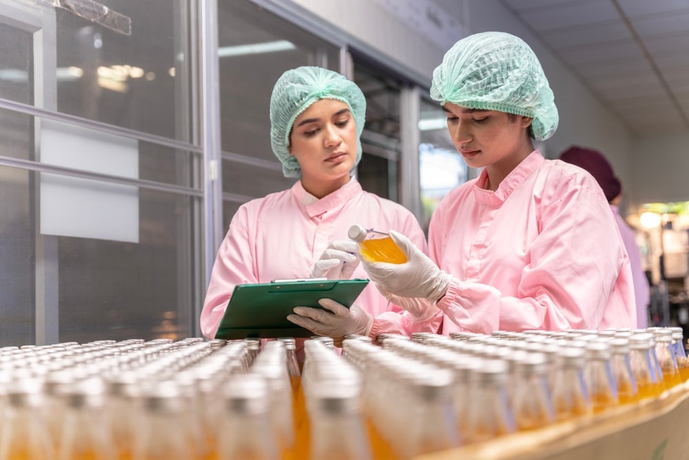 two workers wearing protective gear while checking products in a facility setting